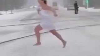 Woman a Towel Runs Through Snow-Covered Street, Dives Under A Car