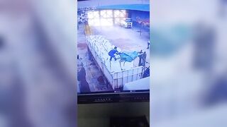 CCTV footage captures the moment a truck driver fell from the top of his vehicle while attempting to pull the truck cover over goods loaded by a forklift, slipping and injuring himself after losing his grip.