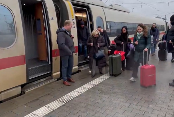 Hillary looking like a Gnome gets off Train in Munich