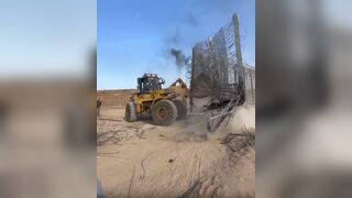 A Palestinian Bulldozer Smashing Open the Separation wall on the Gaza Strip border.
