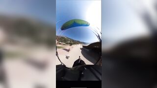 A man lands with a parachute and collides with a man