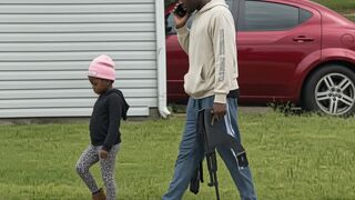 A father was filmed walking his little daughter to school... …armed with a AK-47