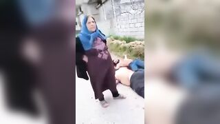 A Shia mother standing beside the bodies of her sons who were killed by HTS