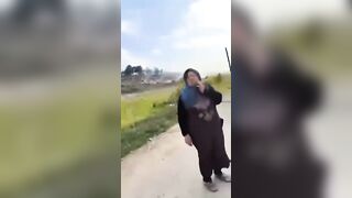 A Shia mother standing beside the bodies of her sons who were killed by HTS