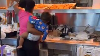 Woman holding her Baby helps Herself to the Chicken. Pay? nah