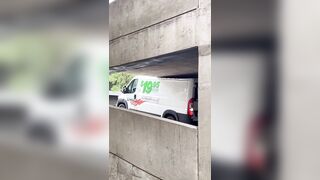 Man in a U-Haul van damaging the roof after driving into a parking garage