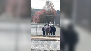 This woman randomly looks over and sees a group of teenagers praying in a circle. Then as they finish she applauds them.